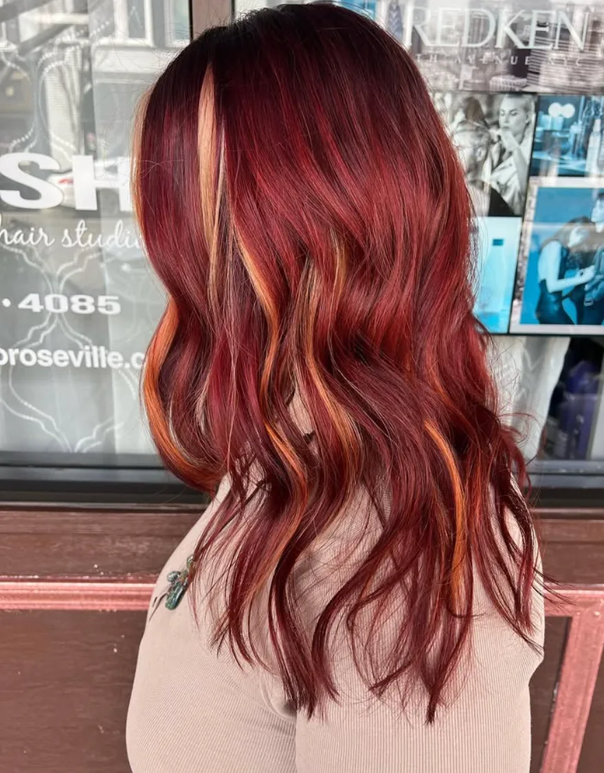 Long ruby-red hair with copper face-framing ribbons and loose waves