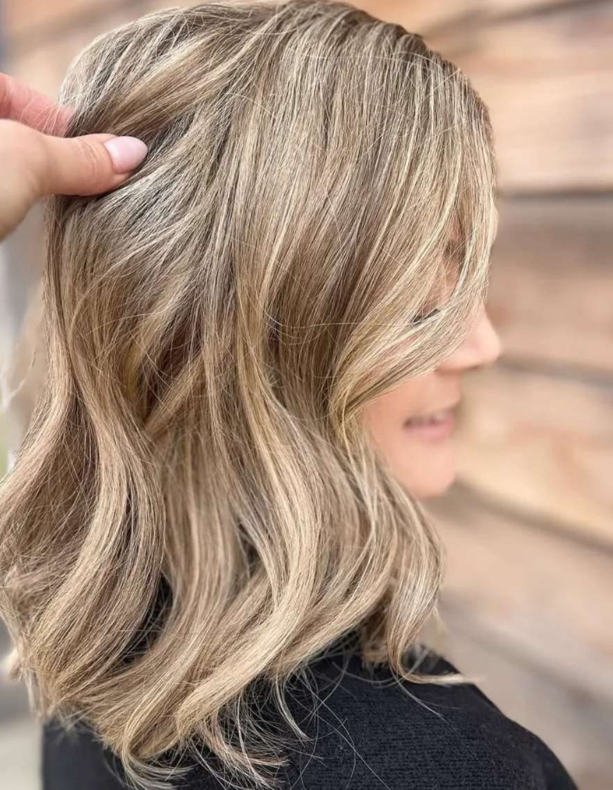 Dimensional beige-blonde hair with a seamless root blend and polished waves