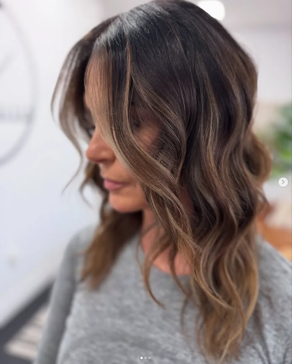 Dimensional brunette hair with caramel face-framing highlights and soft waves